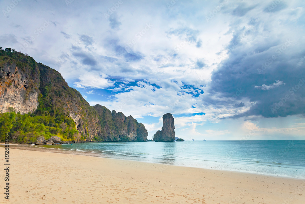 Stunning scene the limestone cliffs covered with the vegetation and the ocean shore on the cloudy sky background. Beauty of wild virgin Thai nature. Ideal place for the calm rest.
