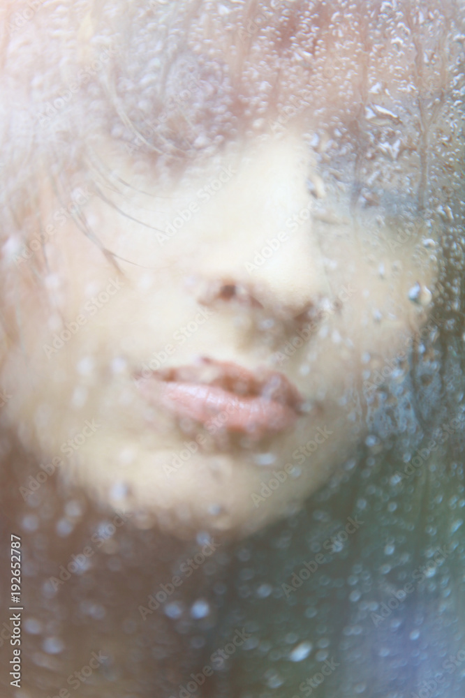 Attractive woman looking out of the window on rainy day