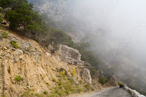 Dangerous winding road in the mountains in a fog. Car on a mountain road. photo