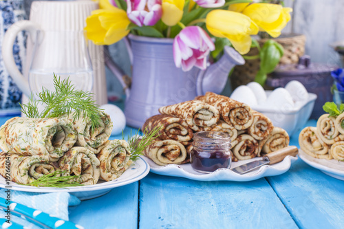 Thin pancakes for the spring Russian holiday with different fillings. Traditional food. Wessing breakfast. Easter and carnival. A bouquet of bright tulips. Blue background. Card. Place for text. photo