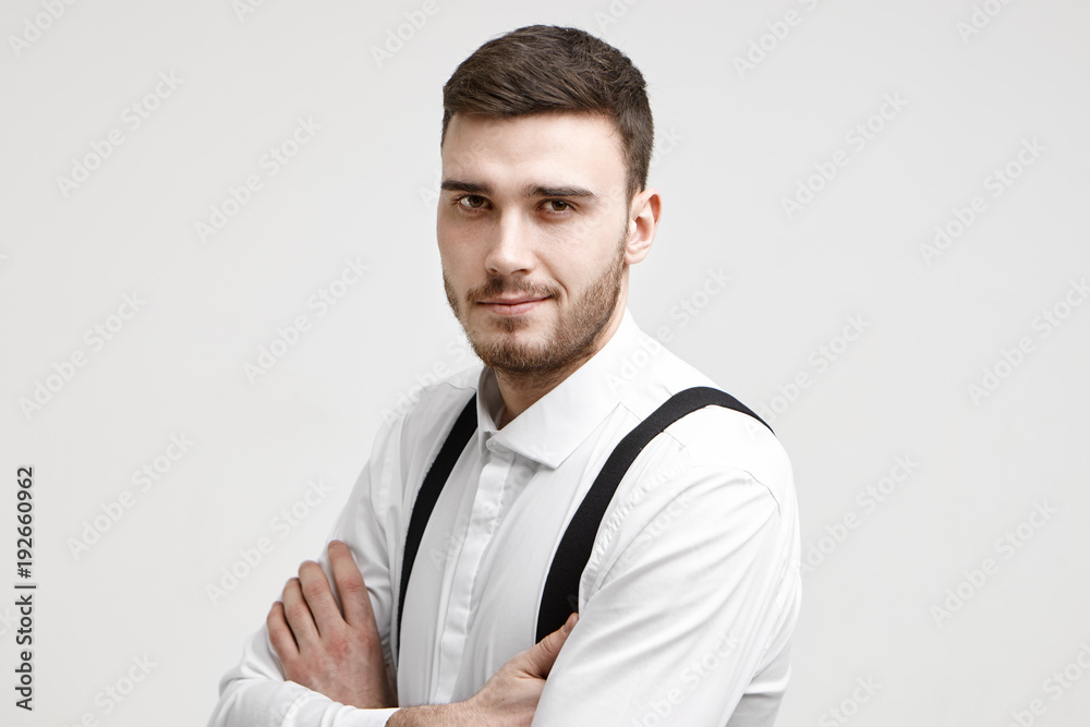 People, work, job, career and employment concept. Picture of attractive self confident prosperous young male manager posing in studio with arms crossed and staring at camera with confident smile People, work, job, career and employment concept. Picture of attractive self confident prosperous young male manager posing in studio with arms crossed and staring at camera with confident smile