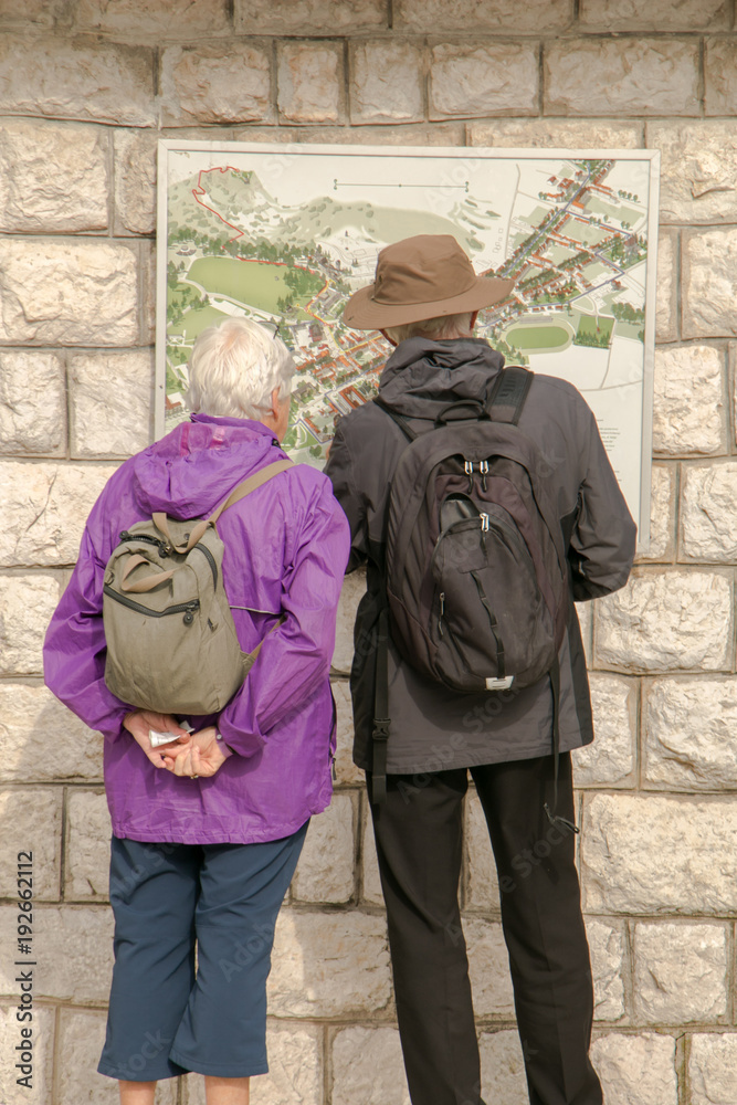 Older tourists looking at a city information board. Tourists in front of the travel map board. Loking at travel map board