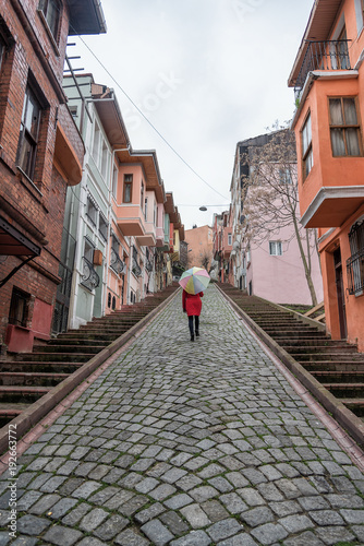 woman under an umbrella walks through the old streets of Istanbul. Colored houses in the Balat district of Istanbul. © Екатерина Спиридонов