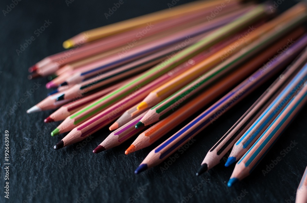 A pile of coloring pencils scattered on a black slate A pile of coloring pencils scattered on a black slate