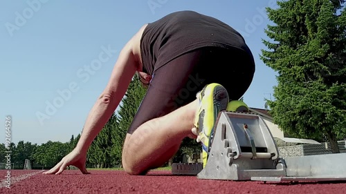 A  100m dash man sprinter starting from the blocks on a tartan at a stadion. Reday, set, go. Slowmotion photo