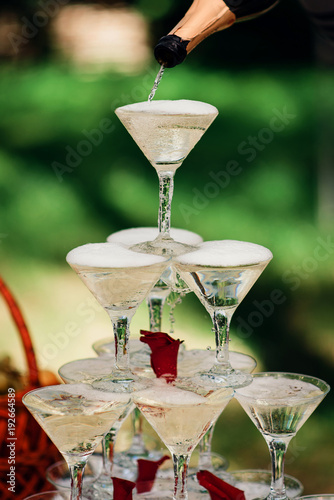 Photography pyramid of champagne glasses for a festive party is filled from the bottle