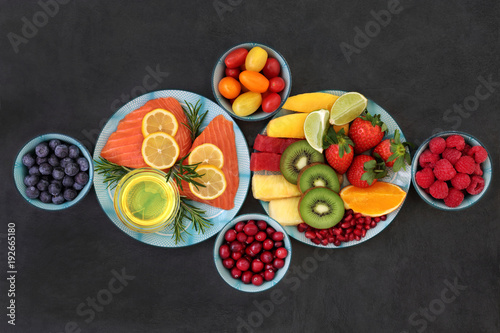 Fototapeta Naklejka Na Ścianę i Meble -  Healthy nutrition for good health concept with super foods of fresh salmon fish, fruit, vegetables, herbs and olive oil very high in antioxidants, anthocyanins, vitamins, minerals and fibre on slate.