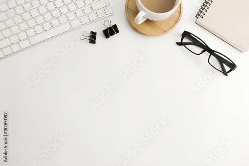 White office desk table with blank notebook, computer, supplies and coffee cup. Top view with copy space. Flat lay. photo