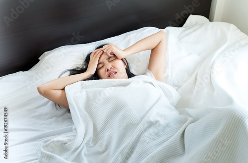 Asian woman have a headache on bed after wake up in the morning