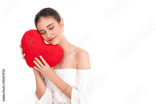 Fototapeta Naklejka Na Ścianę i Meble -  Happy beautiful young woman holding red cushion heart shape smiling isolated in white background with copyspace.love romance and valentines day concept.