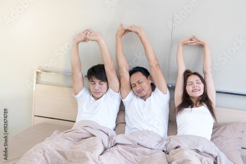Three friends lying on brown bed woke up and stretched in the morning.concept lifestyle