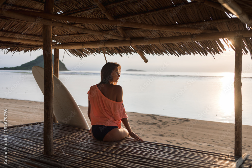 awesome nice brunette girl or woman sitting in the shadow on sunny sandy beach.