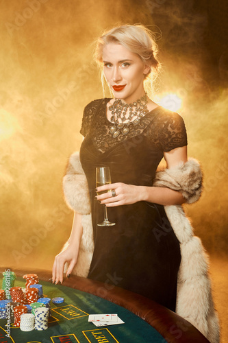 Portrait of woman keeping poker chips near table in casino photo