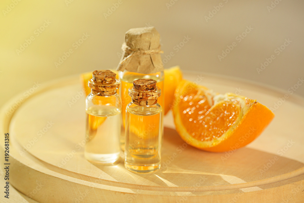 essential orange oil . oil orange in glass bottles and orange slice on a round wooden board on a blurred beige background. organic cosmetics concept essential orange oil . oil orange in glass bottles and orange slice on a round wooden board on a blurred beige background. organic cosmetics concept