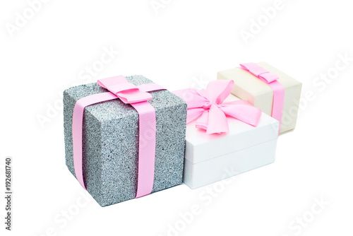 Three festive boxes with gifts tied with satin ribbon on a white background.
