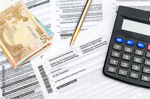 Money, calculator and pen on the German tax form. Top view. 