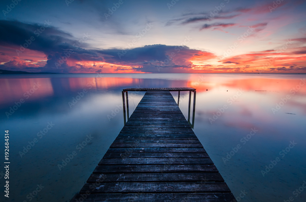 wooden jetty toward horizon during sunset. image contain soft focus and blur due to long expose.