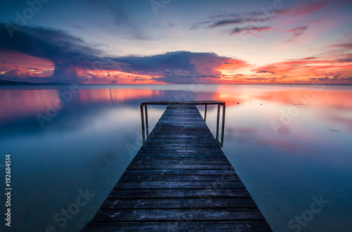 wooden jetty toward horizon during sunset. image contain soft focus and blur due to long expose.