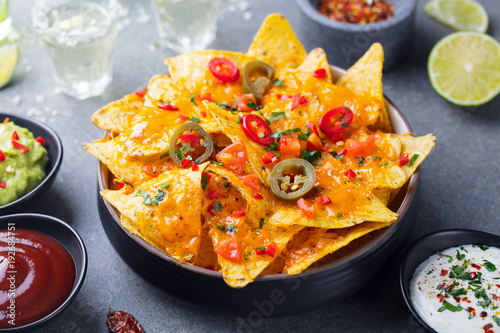 Nachos chips with melted cheese and dips variety.