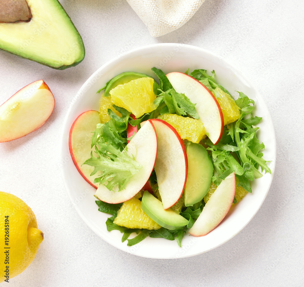 Fruit vegetable salad with red apples, avocado, orange slices Fruit vegetable salad with red apples, avocado, orange slices