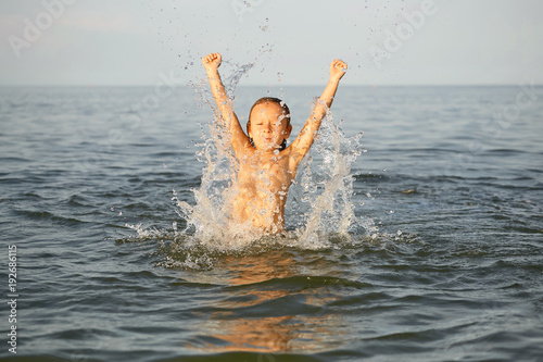 Fototapeta Spray with water. Girl having fun bathing in the sea.