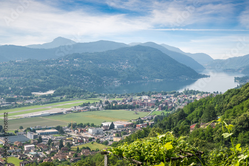 Lake Lugano, Switzerland. Picturesque aerial view of the town of Agno, lake Lugano, Lugano airport on a beautiful summer day. Agno is a municipality in the district of Lugano in the canton of Ticino