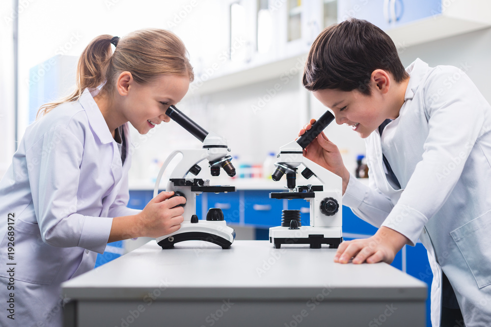 Nice smart children looking into microscopes Nice smart children looking into microscopes