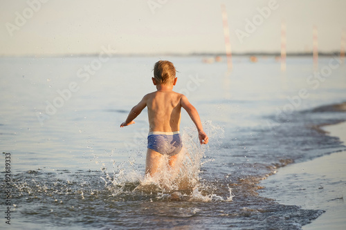 water fun. the boy runs along the seashore © makam1969