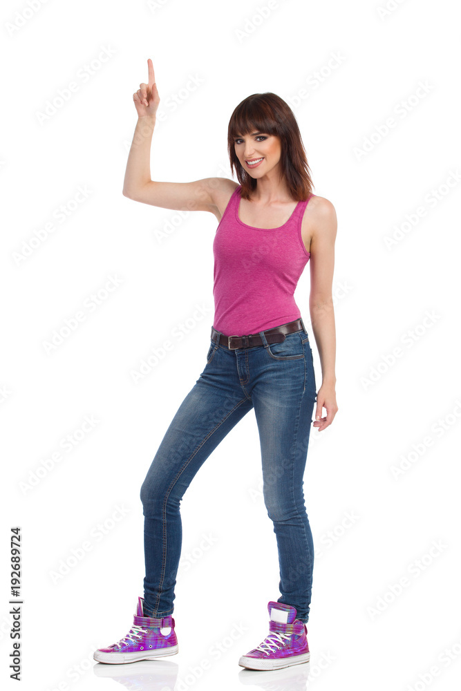 Smiling Casual Woman Is Pointing Up And Looking At Camera Smiling Casual Woman Is Pointing Up And Looking At Camera