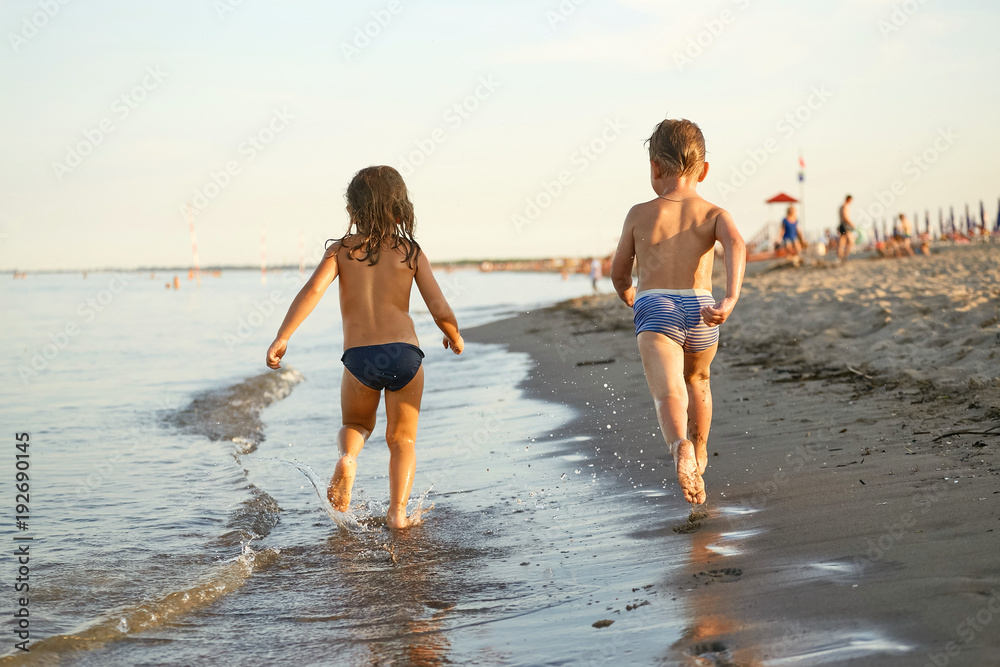 Girl and boy are running along the sea shore