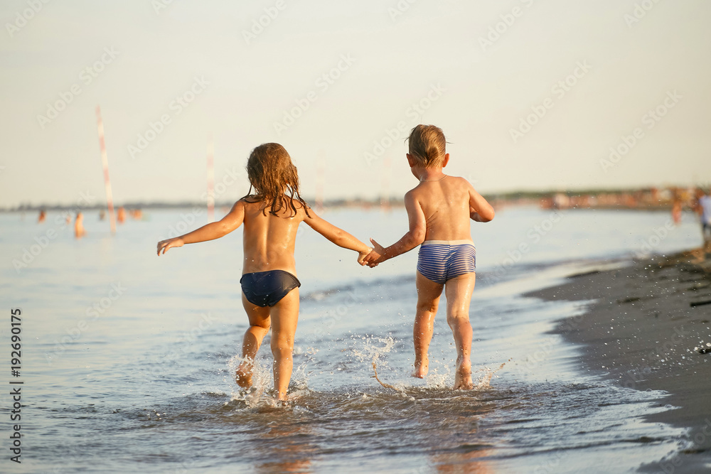 Girl and boy are running along the sea shore Girl and boy are running along the sea shore