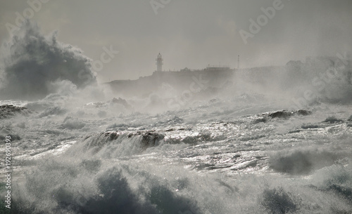 Rough sea, big waves and lighthouse in background, coast of Gran canaria