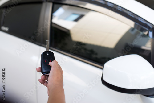 Hand female driver holding car keys with car on background
