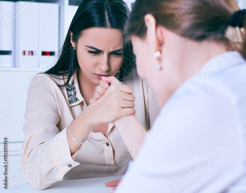 Two female office wokers armwrestling, exerting pressure on each other, struggling for leadership. photo