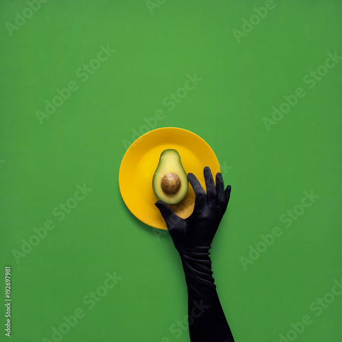Dinner is served / Creative concept photo of avocado with hand on painted plate on green background.