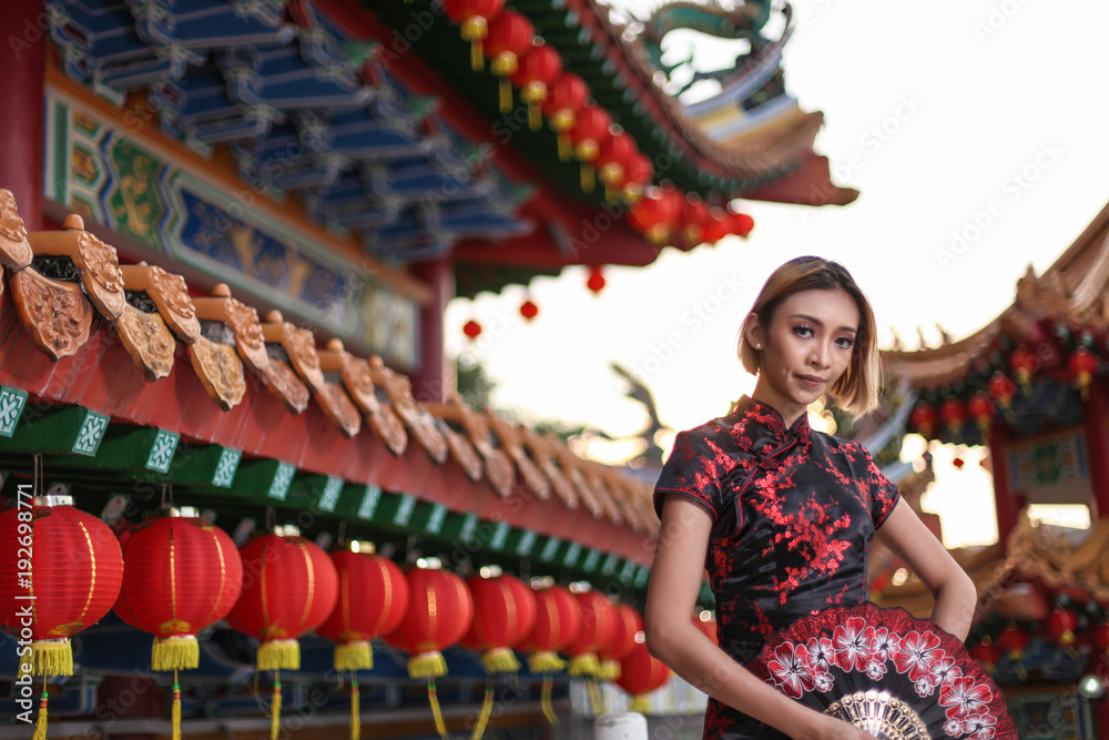 Fototapeta premium asian lady wearing traditional cheongsam dress with temple and lantern background