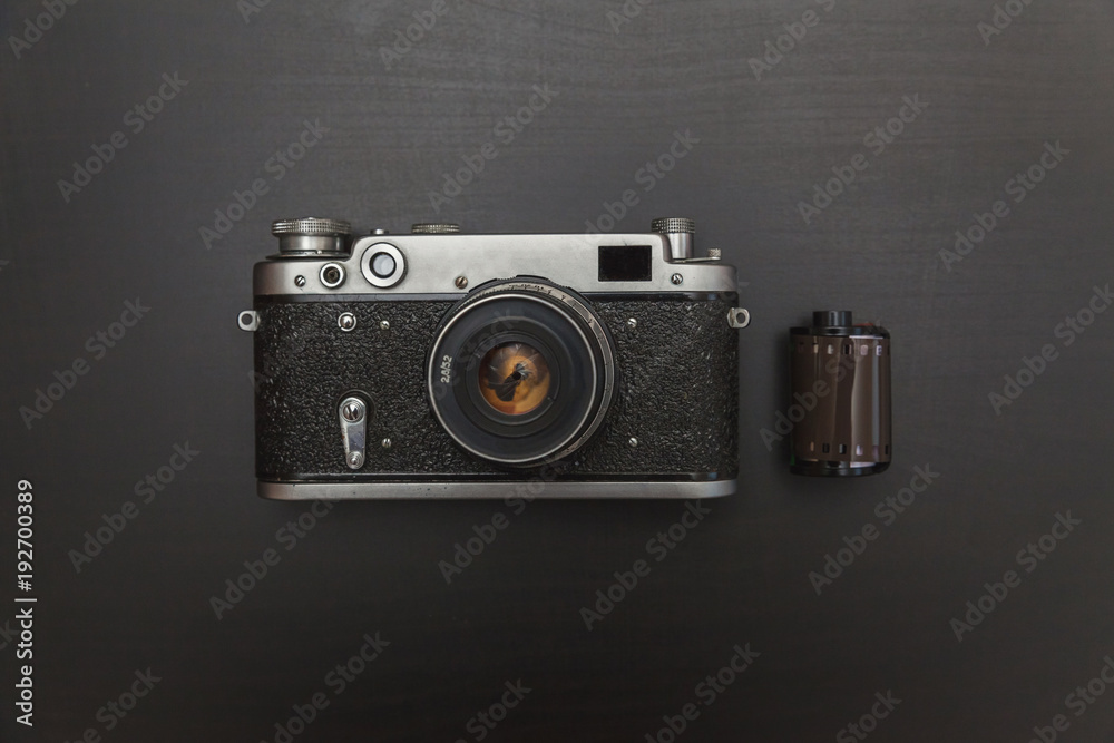 Vintage Film Camera And Roll On Black Wooden Background Technology Development Photographer Concept with copy space. Top View