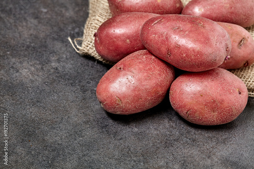 Red potato on black wood table in kitchen. Preperation for cooking.
