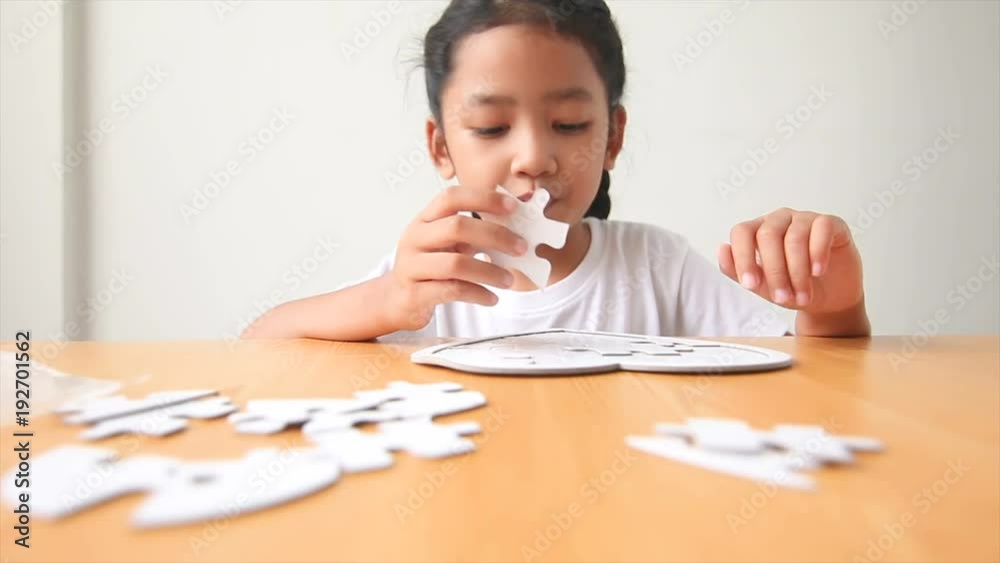 Asian little girl playing jigsaw puzzle select focus on hand shallow depth of field Asian little girl playing jigsaw puzzle select focus on hand shallow depth of field