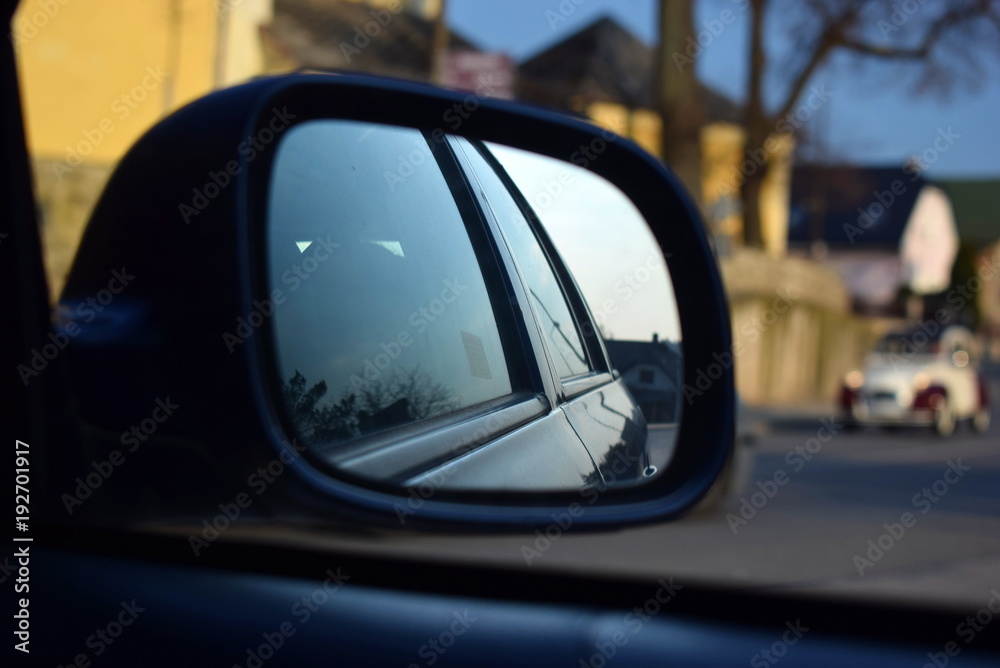 Reflection in car mirror and an old car in background