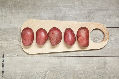 Red potato on black wood table in kitchen. Preperation for cooking.