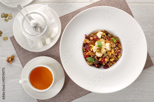muesli on a white plate on white wooden background