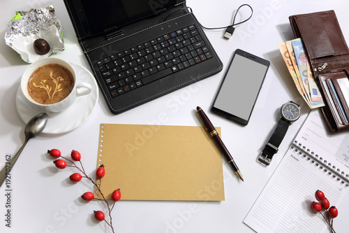 Widok biurka z góry z tabletem, kawą pienidzmi i telefonem.