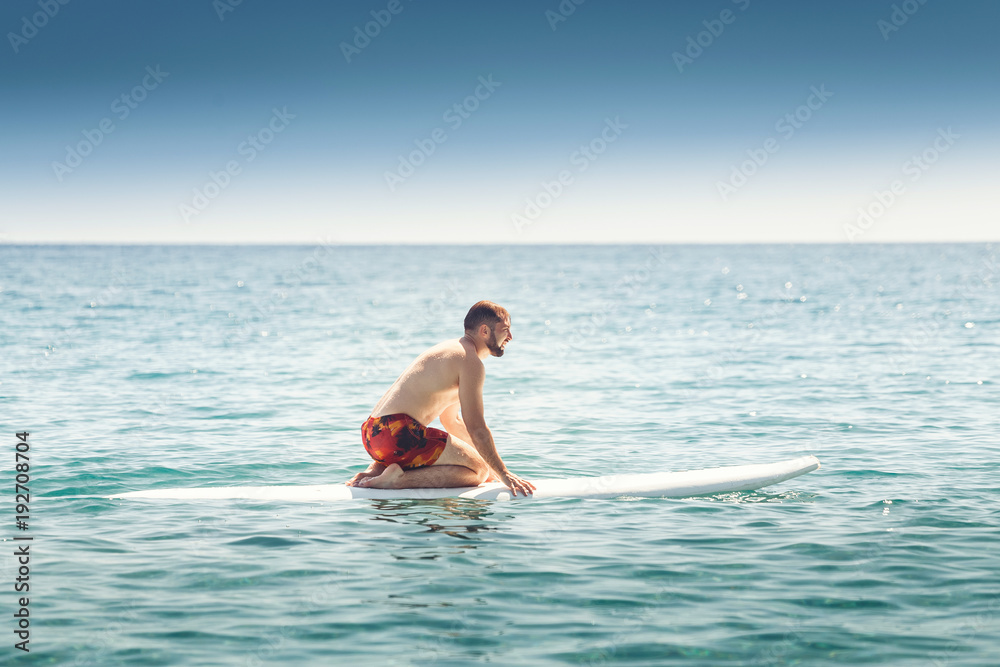 A man learns to ride a water board at the open sea