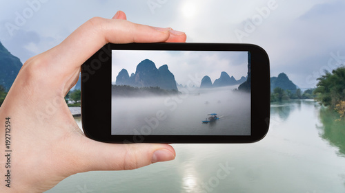 tourist photographs ships in fog on river in China