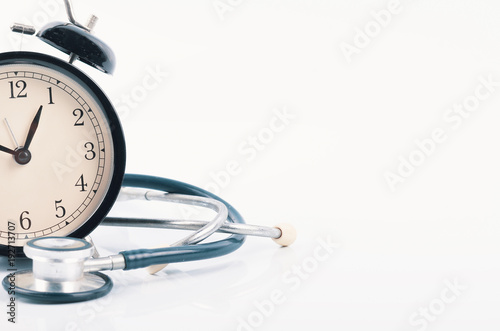 Regular or routine medical examination concept, stethoscope and alarm clock on white background