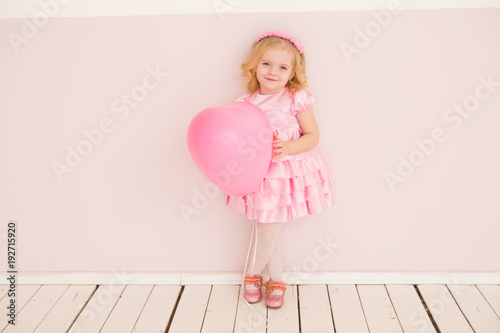 Happy cute little girl  with pink balloon heart on a pink background. mother's day, birthday