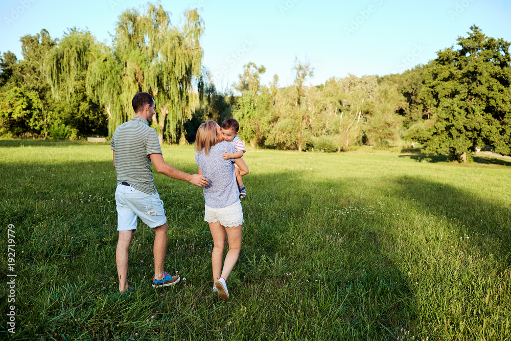 Happy family in nature. Parents with a child play in park.