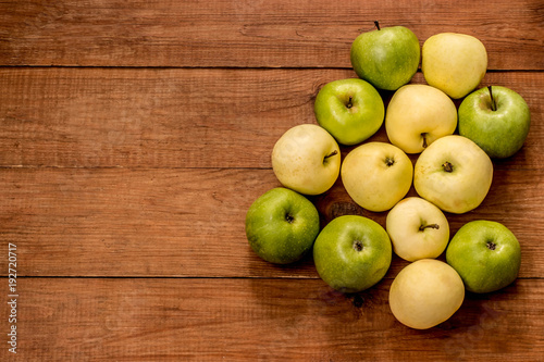 green and yellow apples on a brown wooden background