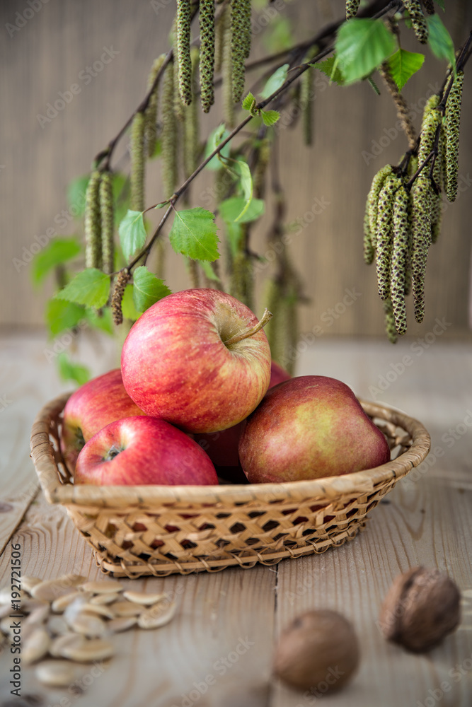 Apples lie in a wicker basket in the form of a heart.